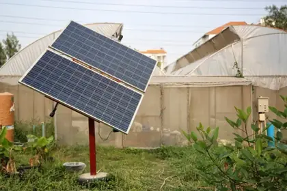Solar panel mounted on a red pole in a garden setting